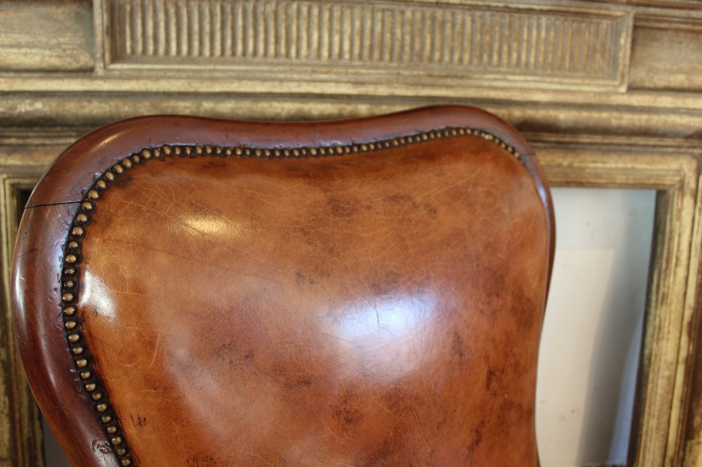 A William IV leather reclining armchair with carved mahogany frame, scrolled arms, brass stud trim, turned front legs, and castors. View VI