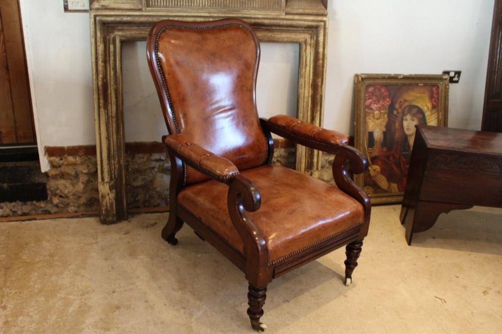 A William IV leather reclining armchair with carved mahogany frame, scrolled arms, brass stud trim, turned front legs, and castors. View VII
