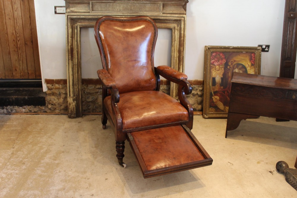 A William IV leather reclining armchair with carved mahogany frame, scrolled arms, brass stud trim, turned front legs, and castors. View IX