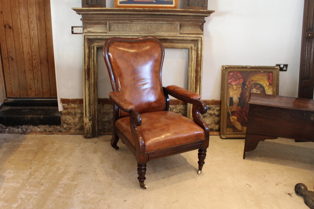 A William IV leather reclining armchair with carved mahogany frame, scrolled arms, brass stud trim, turned front legs, and castors. View X