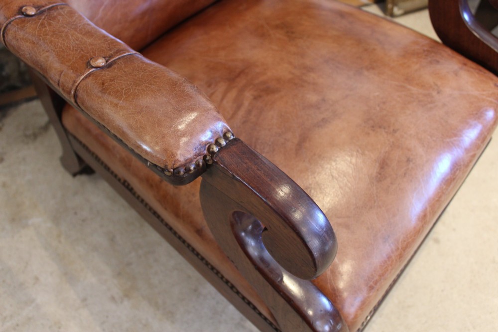 A William IV leather reclining armchair with carved mahogany frame, scrolled arms, brass stud trim, turned front legs, and castors. View XIII