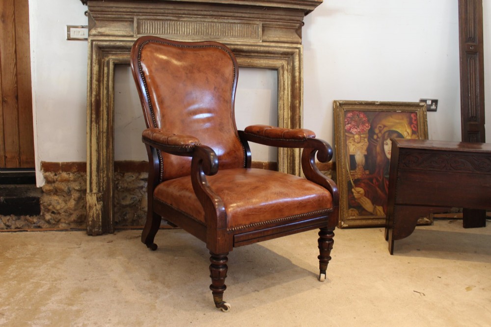 A William IV leather reclining armchair with carved mahogany frame, scrolled arms, brass stud trim, turned front legs, and castors. View XIV