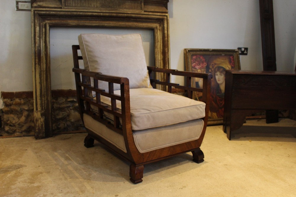 An Art Deco solid walnut armchair featuring grid-pattern side panels, squared feet, and beige suede seat and back cushions.