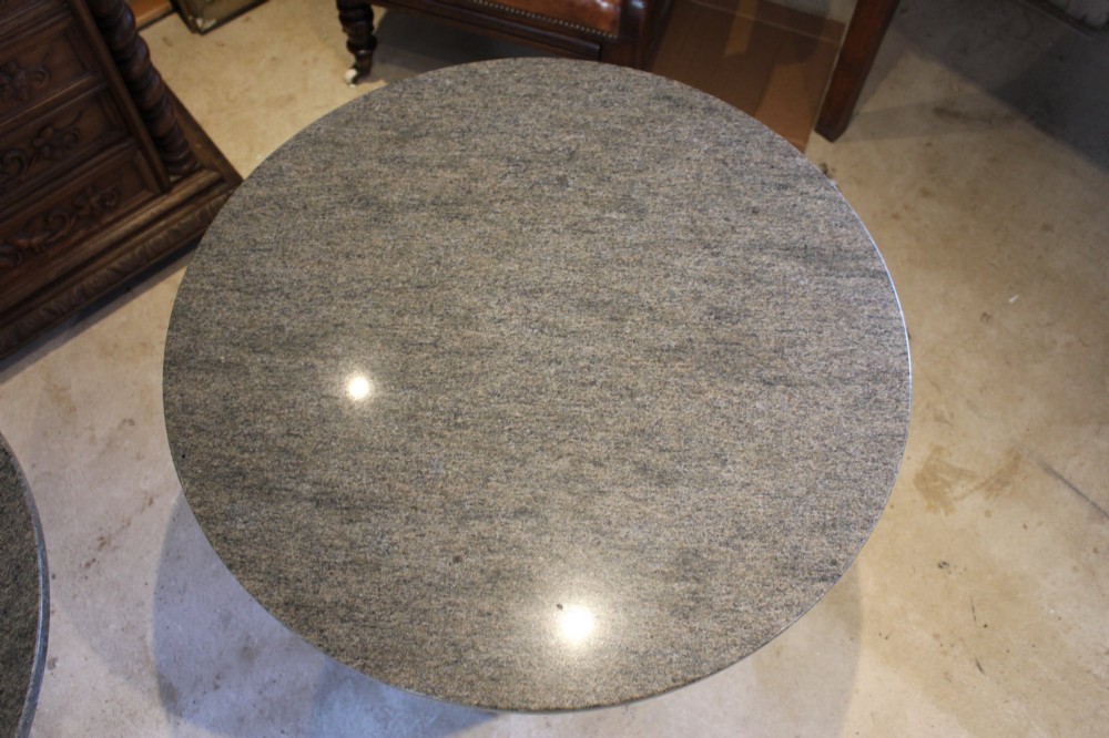 A pair of circular garden tables featuring polished grey granite tops supported by ornate black cast iron pedestal bases with claw feet. View II