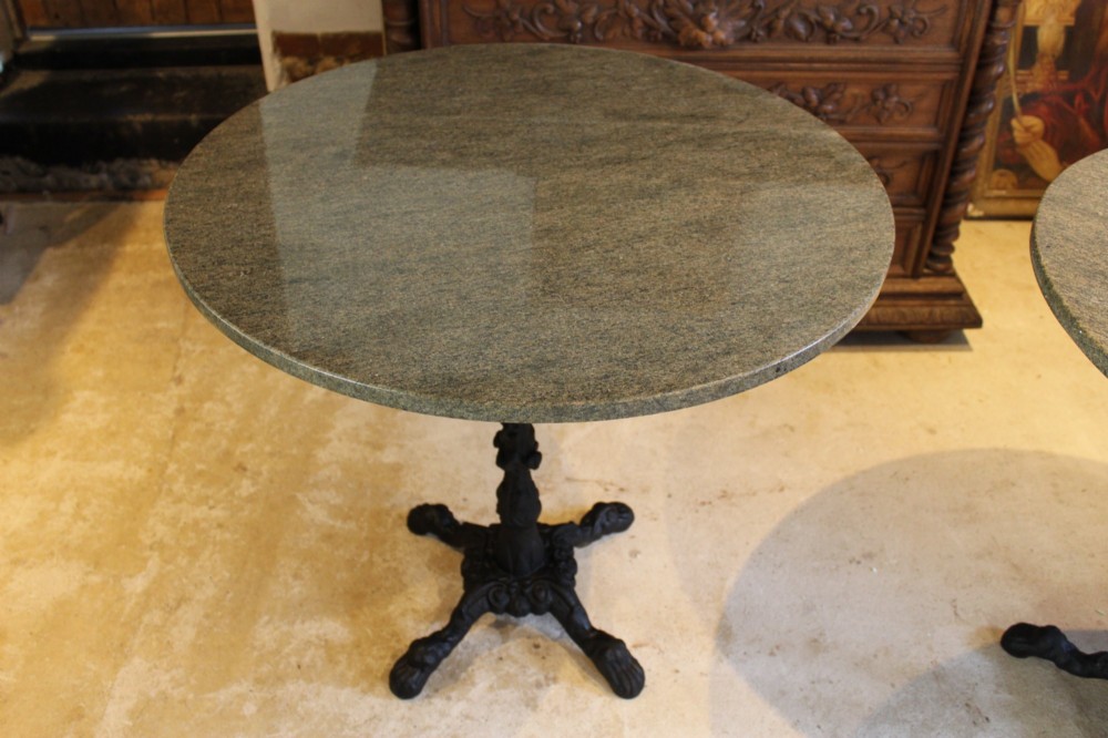 A pair of circular garden tables featuring polished grey granite tops supported by ornate black cast iron pedestal bases with claw feet. View III