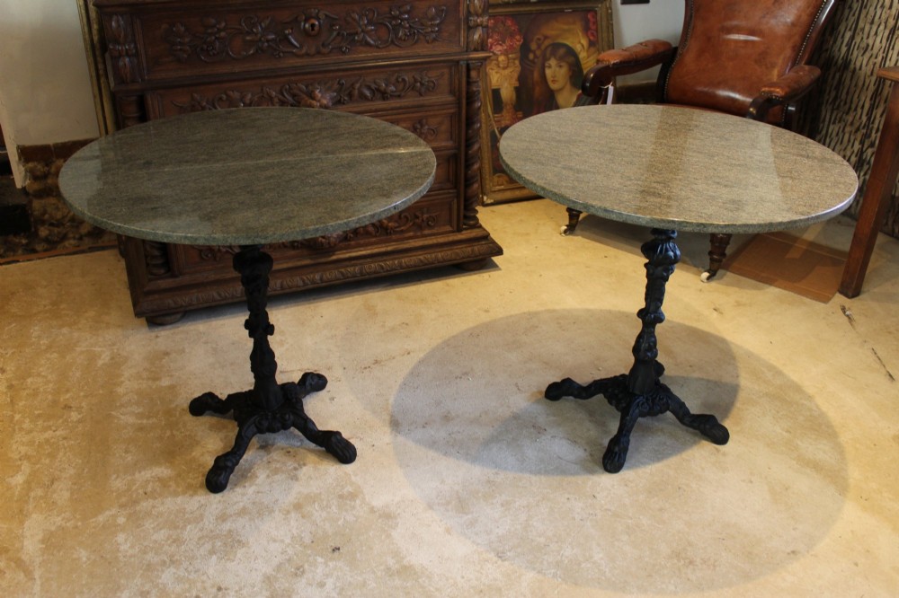 A pair of circular garden tables featuring polished grey granite tops supported by ornate black cast iron pedestal bases with claw feet. View IV