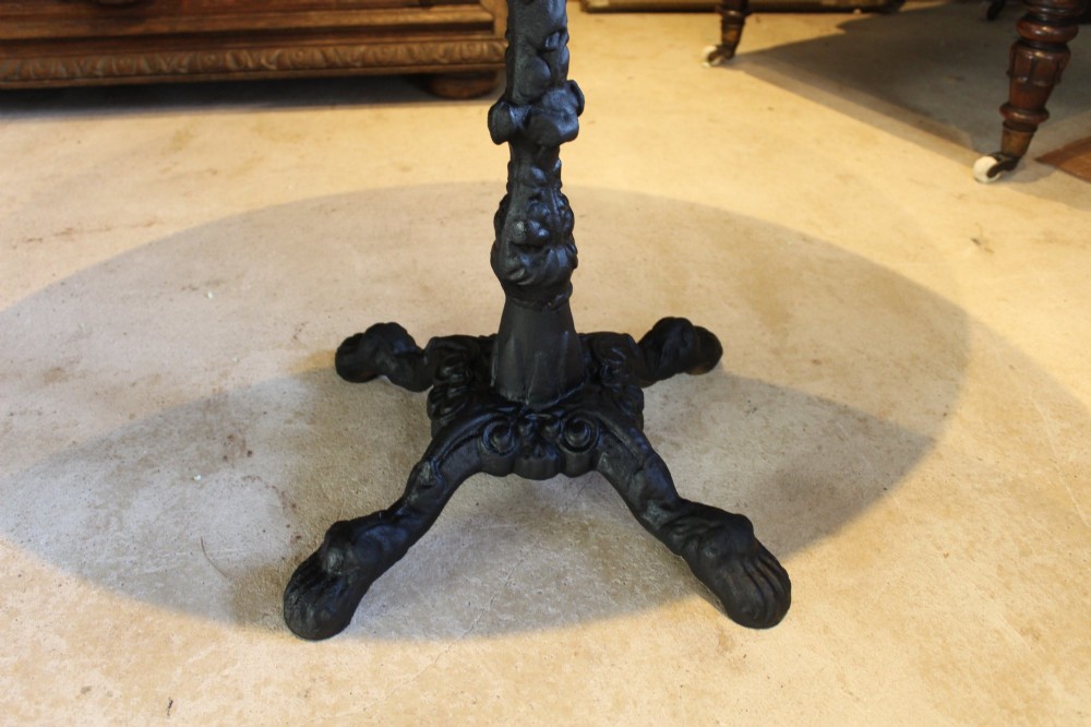 A pair of circular garden tables featuring polished grey granite tops supported by ornate black cast iron pedestal bases with claw feet. View VI