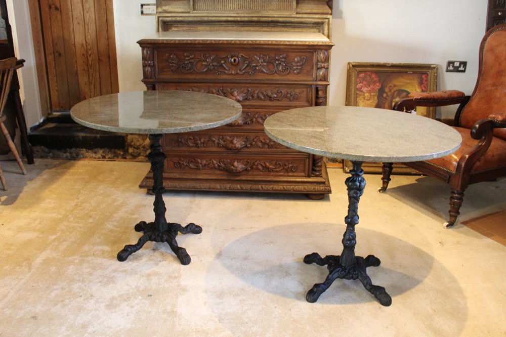A pair of circular garden tables featuring polished grey granite tops supported by ornate black cast iron pedestal bases with claw feet. View VIII