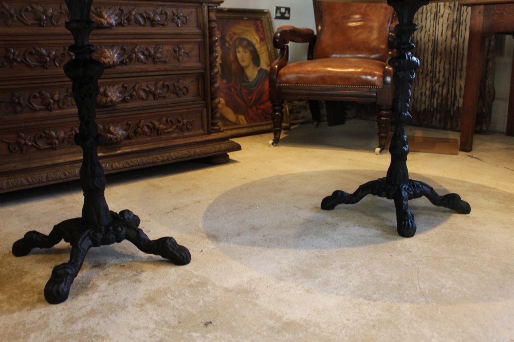 A pair of circular garden tables featuring polished grey granite tops supported by ornate black cast iron pedestal bases with claw feet. View IX
