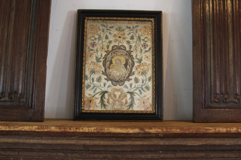 A framed 17th-century silk embroidery panel depicting a central oval medallion with a haloed figure surrounded by detailed floral scrollwork in a dark moulding frame. View VIII