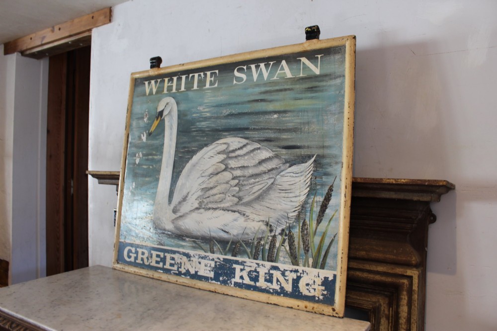A double-sided rectangular painted metal pub sign depicting a white swan floating on blue water with White Swan text above and Greene King text below. View II