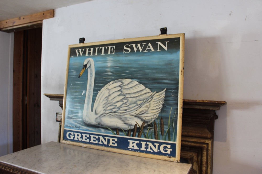 A double-sided rectangular painted metal pub sign depicting a white swan floating on blue water with White Swan text above and Greene King text below. View VIII