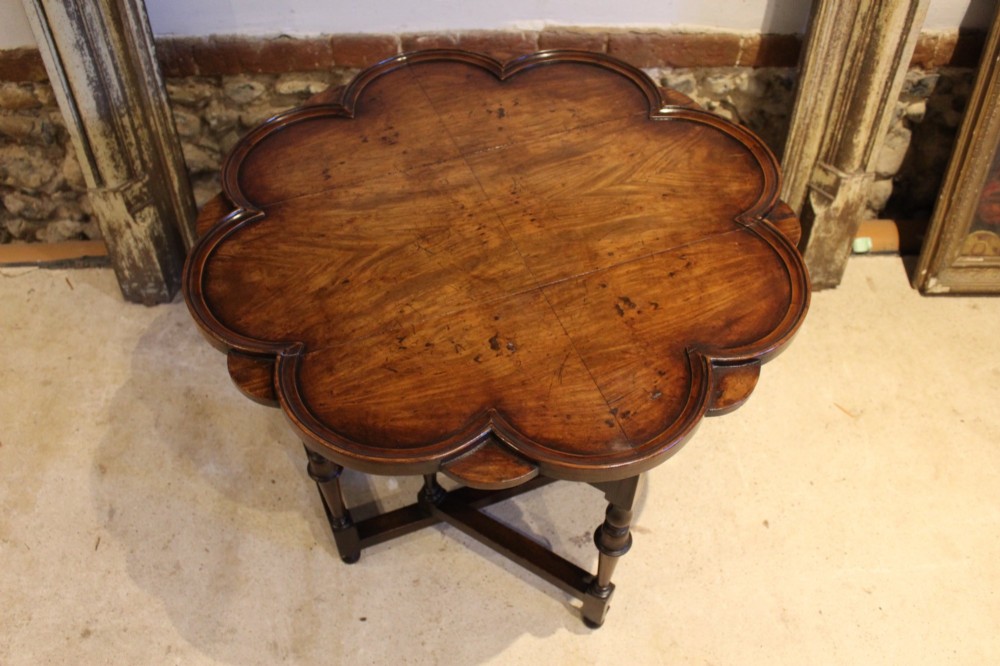 A late Victorian walnut occasional table featuring a scalloped multi-lobed top with a raised rim, supported by turned legs and cross stretchers.