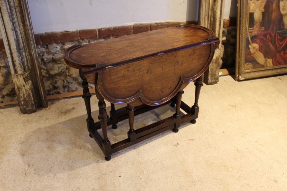 A late Victorian walnut occasional table featuring a scalloped multi-lobed top with a raised rim, supported by turned legs and cross stretchers. View IV