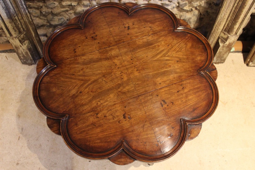 A late Victorian walnut occasional table featuring a scalloped multi-lobed top with a raised rim, supported by turned legs and cross stretchers. View VI