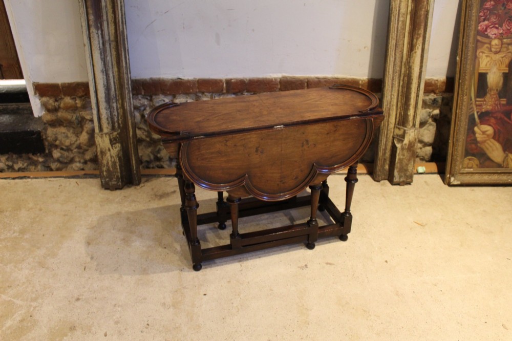 A late Victorian walnut occasional table featuring a scalloped multi-lobed top with a raised rim, supported by turned legs and cross stretchers. View IX