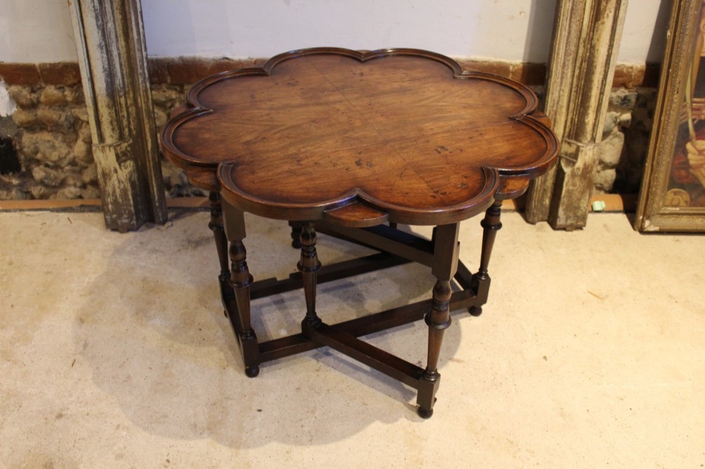 A late Victorian walnut occasional table featuring a scalloped multi-lobed top with a raised rim, supported by turned legs and cross stretchers. View X