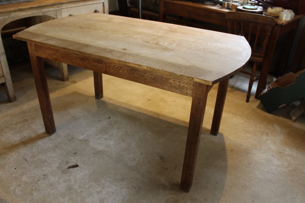 An Edwardian light oak dining table featuring a rectangular top with subtly curved short ends, supported by four straight square legs. View IX