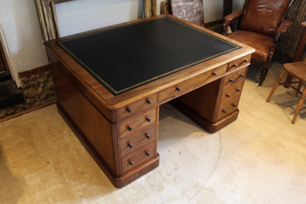 An early Victorian mahogany partners desk featuring a black leather writing top, twin pedestals with multiple drawers, and turned wooden handles. View IX