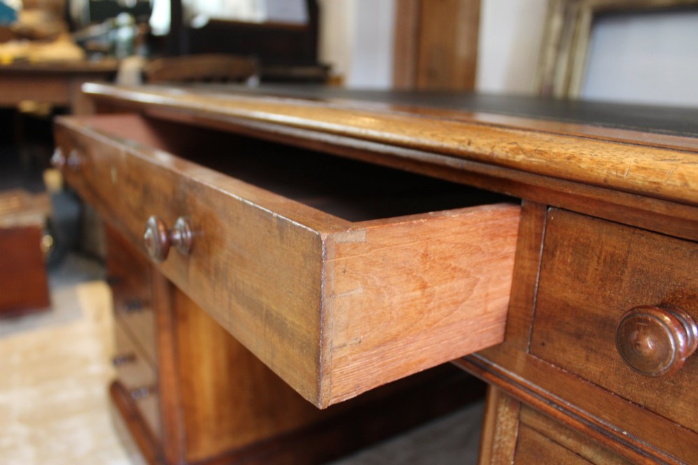 An early Victorian mahogany partners desk featuring a black leather writing top, twin pedestals with multiple drawers, and turned wooden handles. View XII