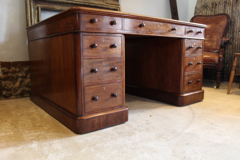 An early Victorian mahogany partners desk featuring a black leather writing top, twin pedestals with multiple drawers, and turned wooden handles. View XIV