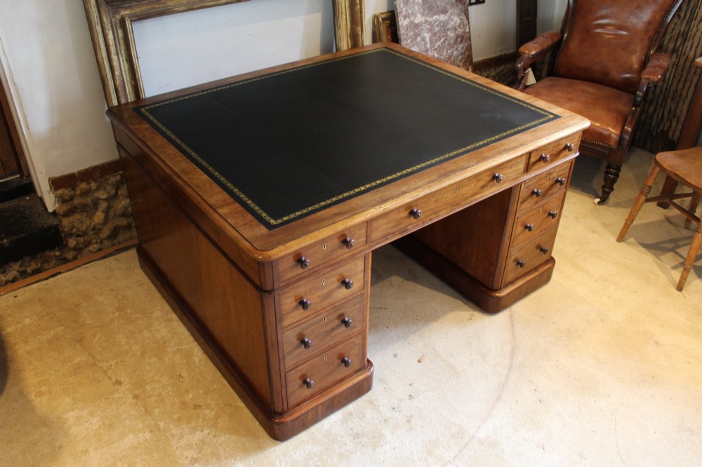 An early Victorian mahogany partners desk featuring a black leather writing top, twin pedestals with multiple drawers, and turned wooden handles. View XV