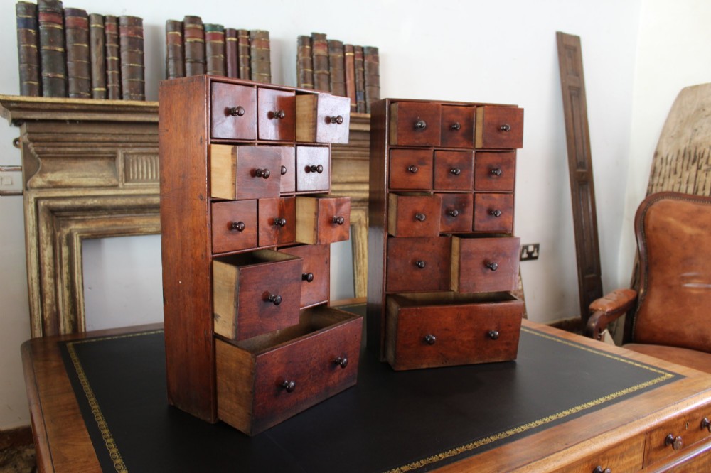 A pair of matching early nineteenth-century tabletop wooden apothecary chests featuring multiple small drawers with turned wooden knobs and a warm brown finish. View XI