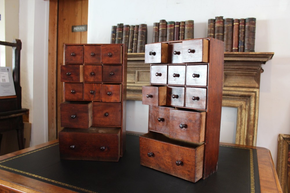 A pair of matching early nineteenth-century tabletop wooden apothecary chests featuring multiple small drawers with turned wooden knobs and a warm brown finish. View XII