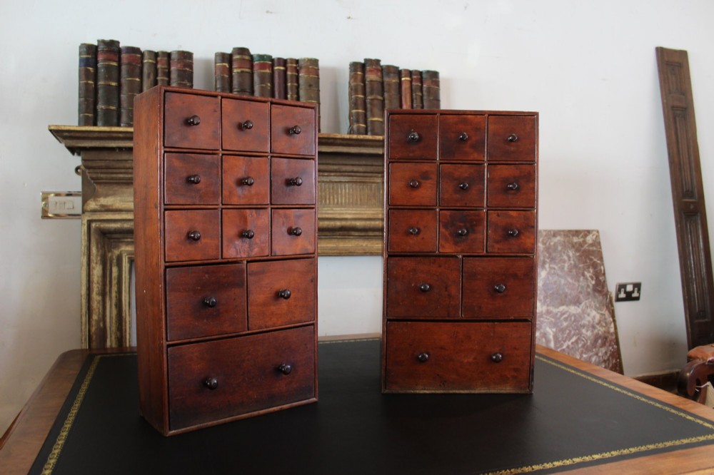 A pair of matching early nineteenth-century tabletop wooden apothecary chests featuring multiple small drawers with turned wooden knobs and a warm brown finish. View XIII