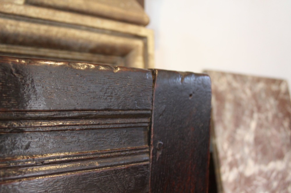 A dark oak 17th-century style settle bench with a three-panel backrest, shaped armrests, and wooden stretchers. View VI