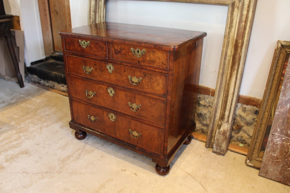 A compact George II walnut chest of drawers featuring decorative brass handles, crossbanded veneer top, and turned bun feet. View XIII