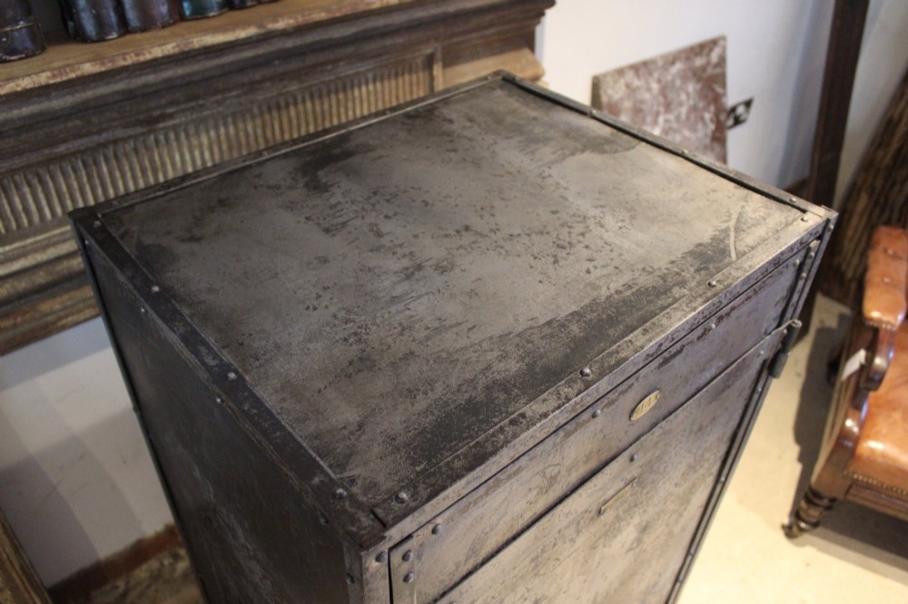 A tall, narrow Victorian industrial metal cupboard featuring a single door with a dark grey patinated surface, riveted frame, brass number plaque, and latch handle. View VIII