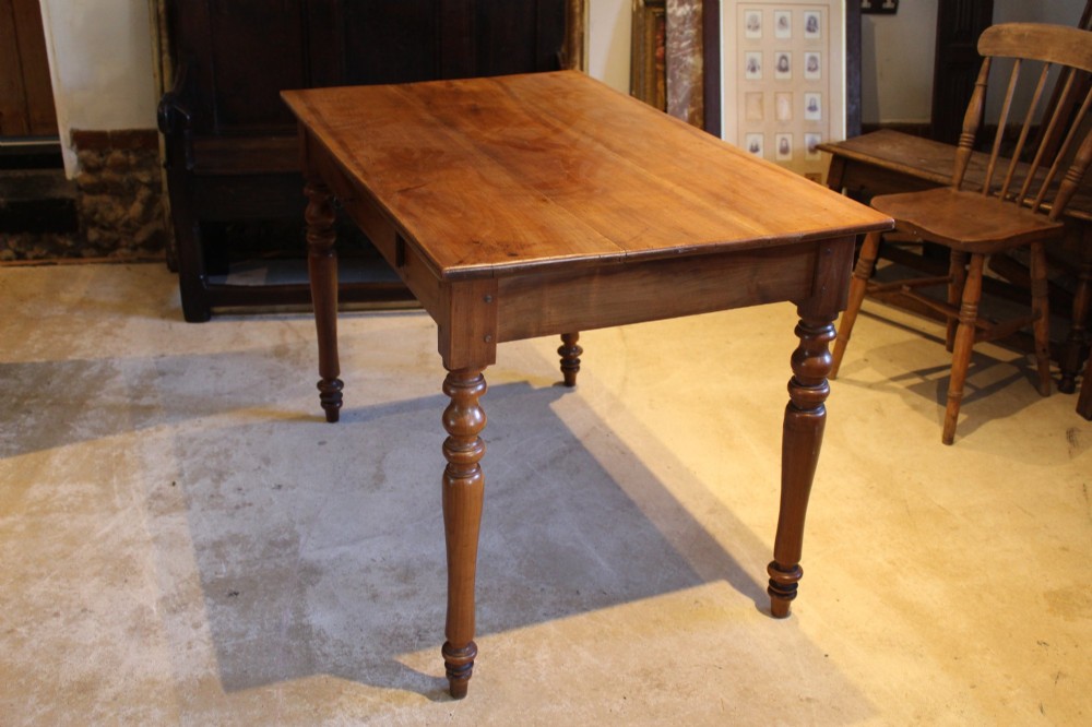 A rectangular French cherry wood dining table featuring four turned legs and a single frieze drawer. View VI