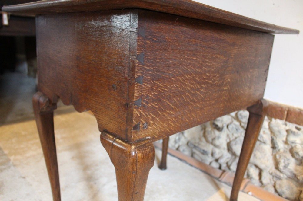 A George II oak lowboy table featuring a single drawer with brass handles, a scalloped apron, and slender cabriole legs ending in pad feet. View X