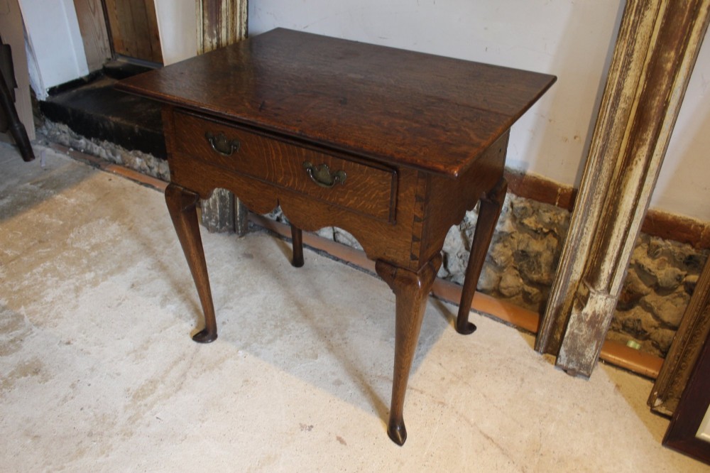 A George II oak lowboy table featuring a single drawer with brass handles, a scalloped apron, and slender cabriole legs ending in pad feet. View XIII