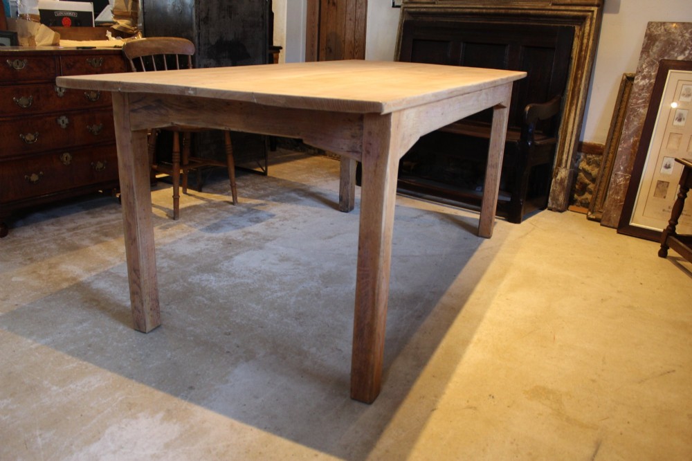 An Edwardian light oak farmhouse refectory dining table featuring straight square legs and a spacious rectangular plank top.