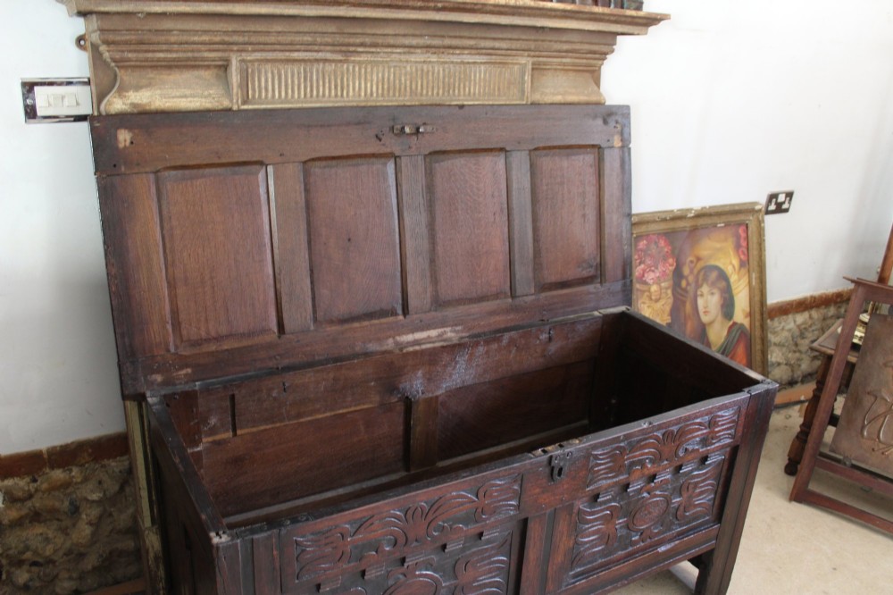 A 17th-century dark oak coffer featuring carved front panels and a four-panel hinged lid. View V