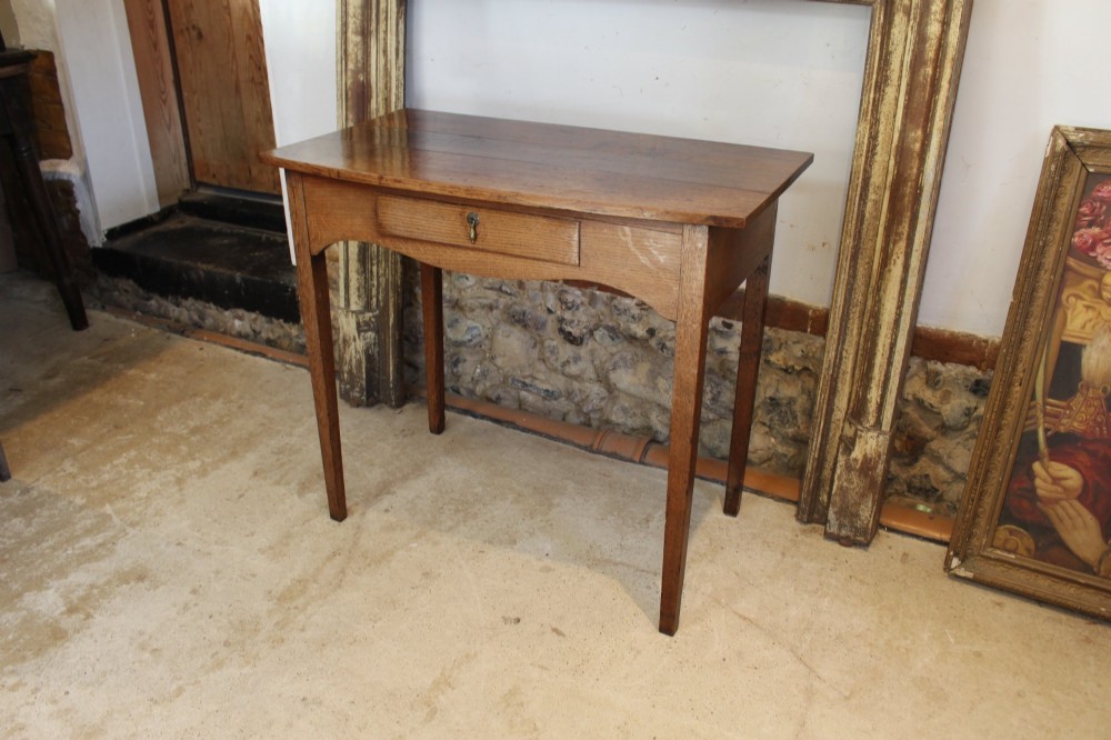 A George III country oak side table featuring a single frieze drawer with a brass drop handle, a shaped apron, and four straight legs. View II