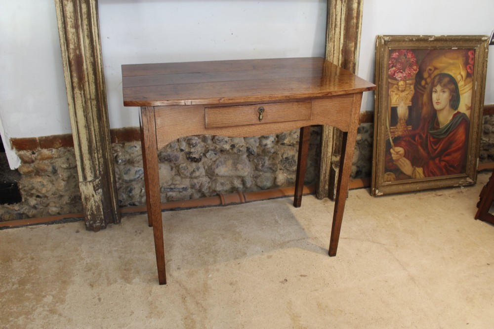 A George III country oak side table featuring a single frieze drawer with a brass drop handle, a shaped apron, and four straight legs. View III