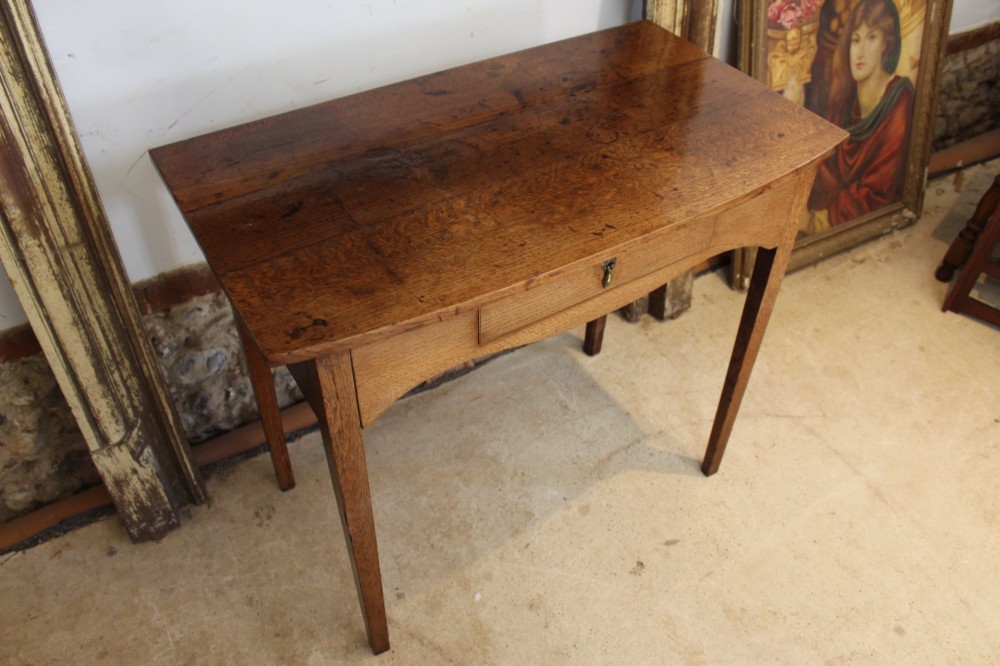 A George III country oak side table featuring a single frieze drawer with a brass drop handle, a shaped apron, and four straight legs. View VI
