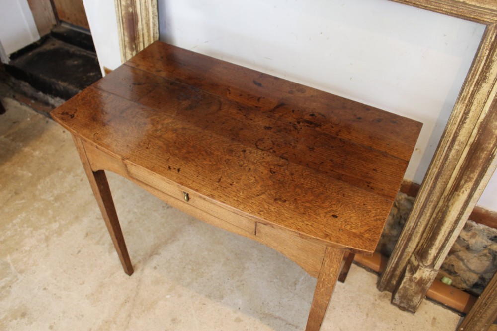 A George III country oak side table featuring a single frieze drawer with a brass drop handle, a shaped apron, and four straight legs. View IX