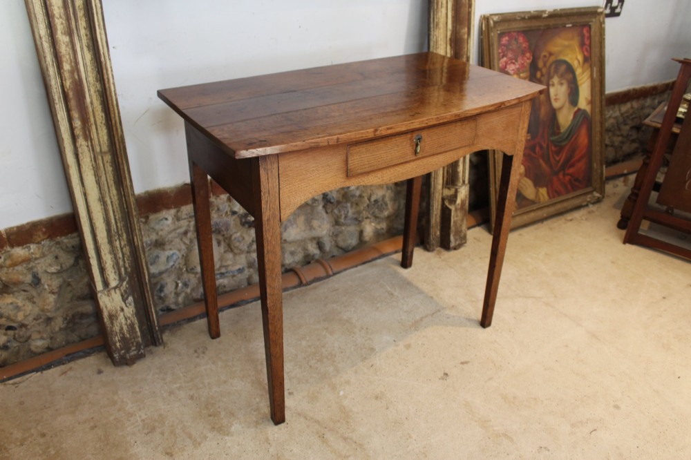 A George III country oak side table featuring a single frieze drawer with a brass drop handle, a shaped apron, and four straight legs. View XI