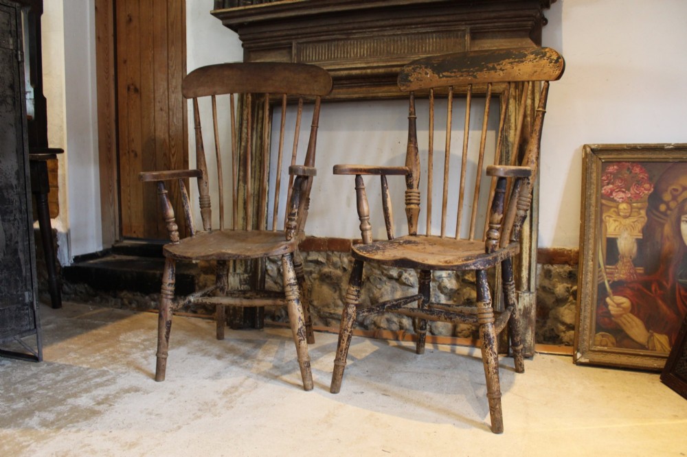A pair of late 19th-century Windsor armchairs featuring shaped elm seats, spindle backs, turned legs, and distressed dark brown patinated finish. View X