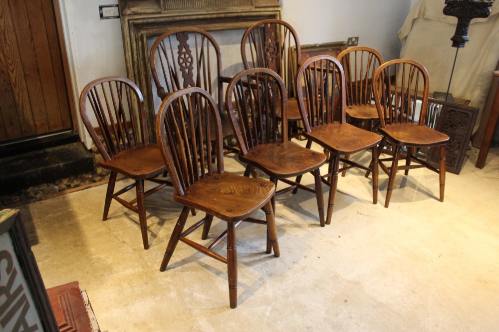 A set of eight Edwardian elm and beech Windsor dining chairs, including two armchairs and six side chairs, featuring hoop backs with spindle uprights and turned legs.