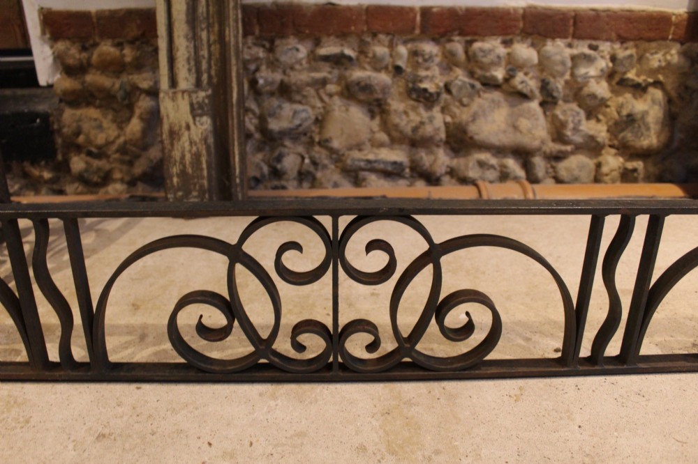 A large dark steel fire fender featuring decorative scrolling ironwork along the front and side returns. View V