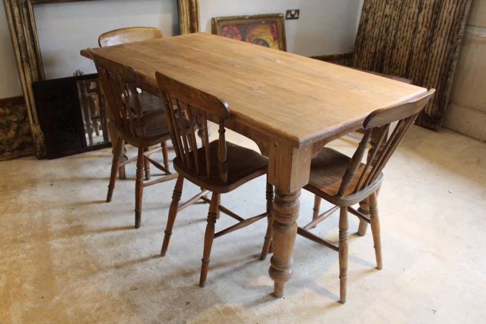An Edwardian rectangular pitch pine dining table with a thick plank top and four stout turned legs. View II