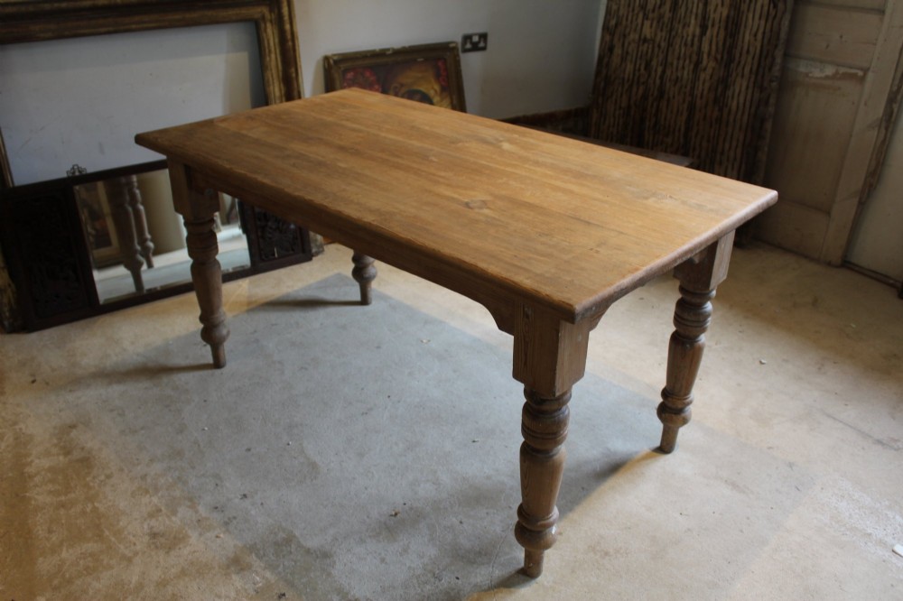 An Edwardian rectangular pitch pine dining table with a thick plank top and four stout turned legs. View III