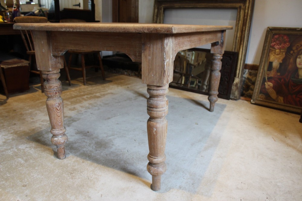 An Edwardian rectangular pitch pine dining table with a thick plank top and four stout turned legs. View VII
