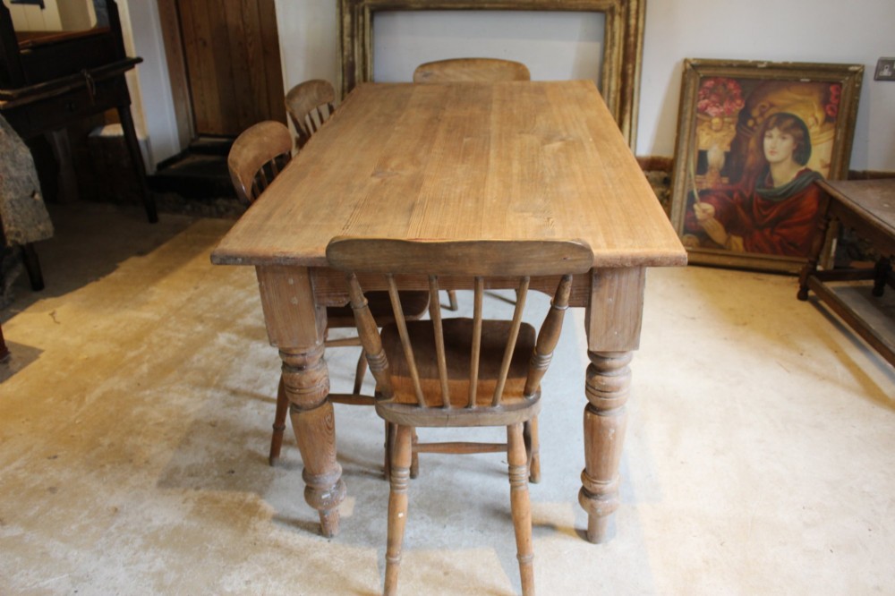An Edwardian rectangular pitch pine dining table with a thick plank top and four stout turned legs. View IX