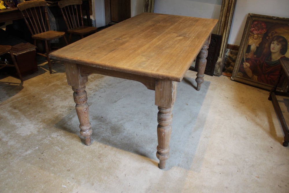 An Edwardian rectangular pitch pine dining table with a thick plank top and four stout turned legs. View X